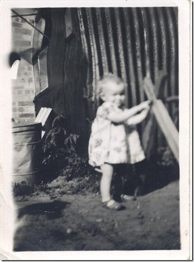 Photo:Linda toddling outside the hut where she was born